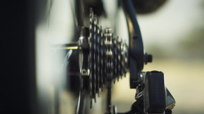 Close up back view of bicycle chain spinning on gears
