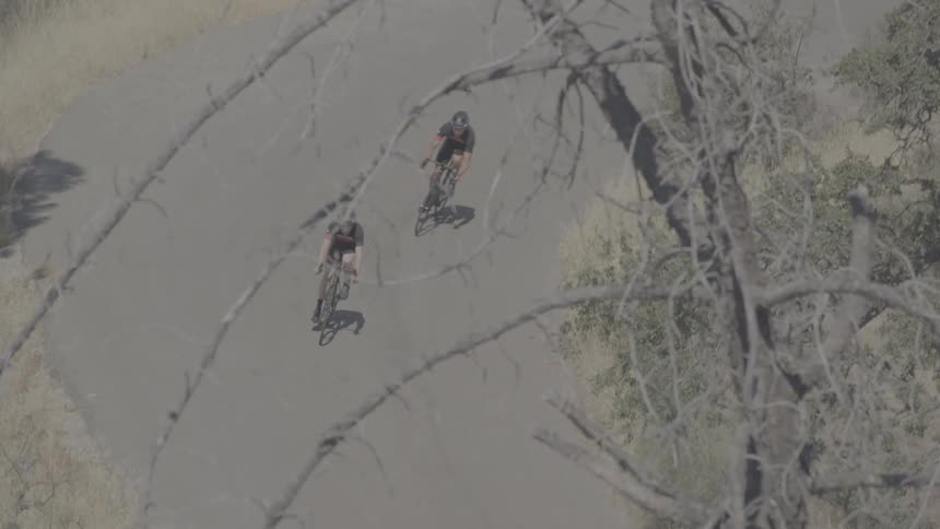 Two bicyclists navigate a turn on a rural road