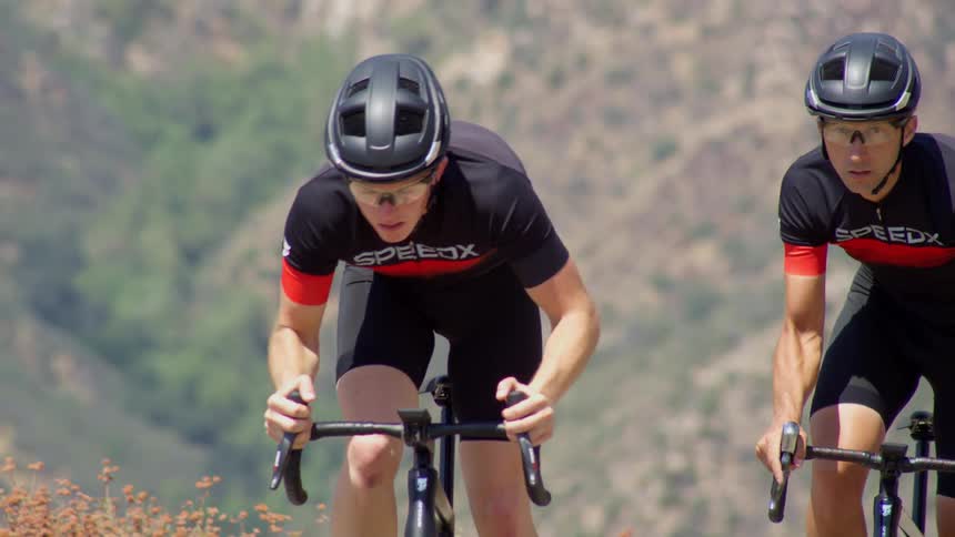 Two cyclists wearing helmets ride their bikes outdoors