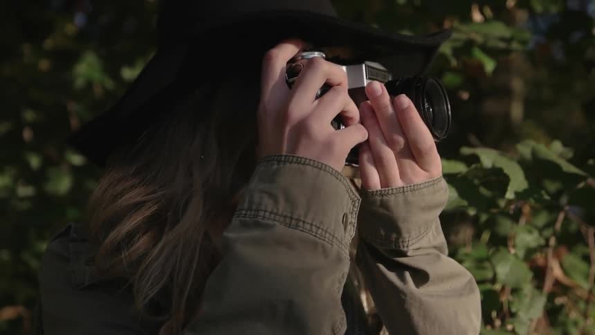 A woman wearing a black hat is taking photographs