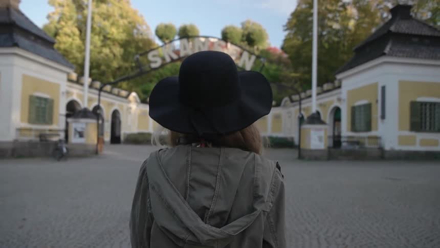 A woman is walking towards a building on a sunny day
