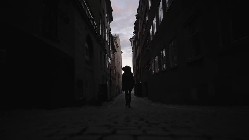 A woman is walking down a dark alley
