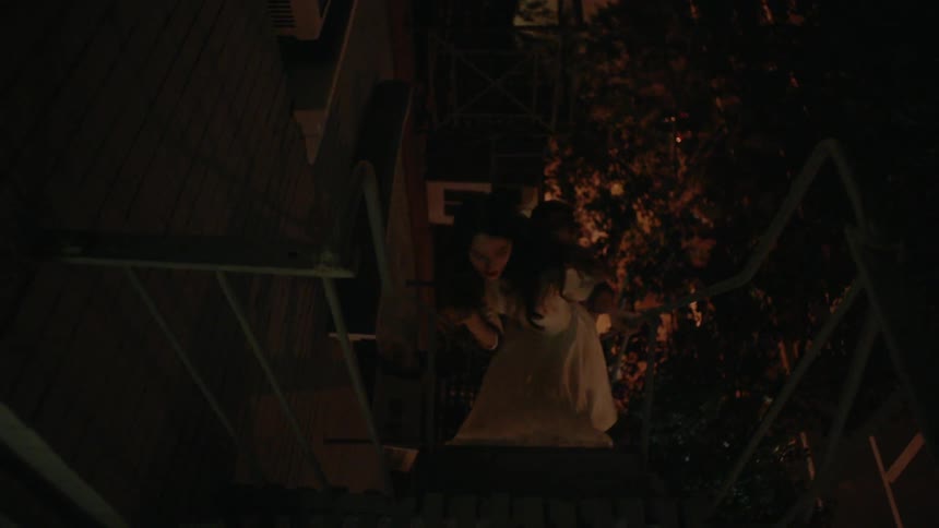 A man and woman quickly descend a fire escape ladder