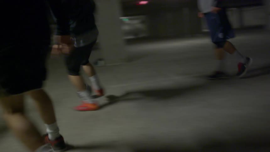 A group of teenage boys play soccer in a parking garage