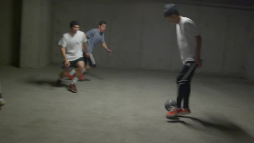 A group of teenage boys kick a ball around