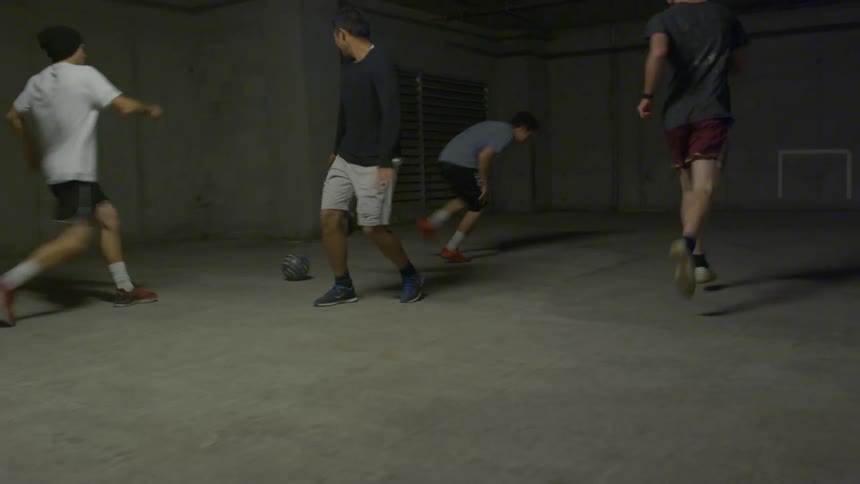 Group of friends play indoor soccer in a parking garage
