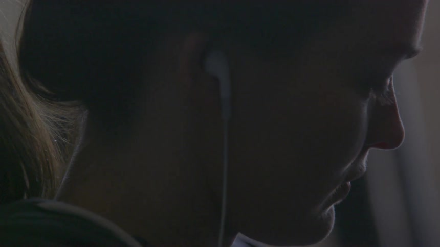 A woman wearing earbuds stretches something with her hands