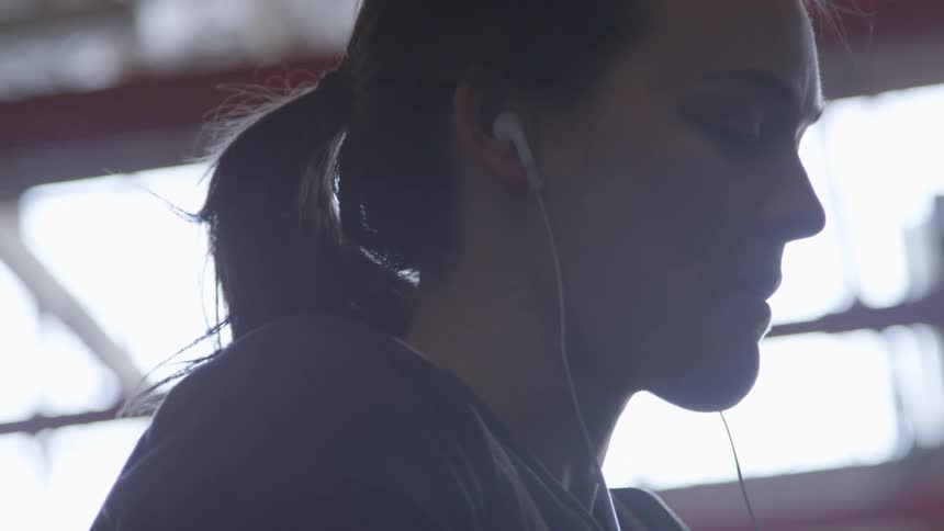 A woman wraps her hands for boxing while wearing headphones