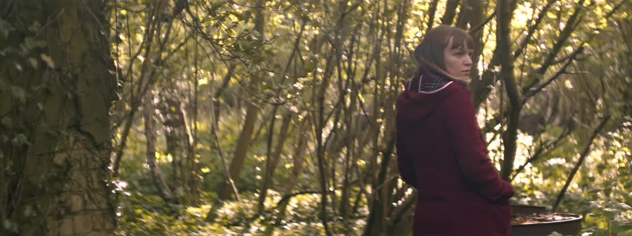 A woman is standing in a forest area