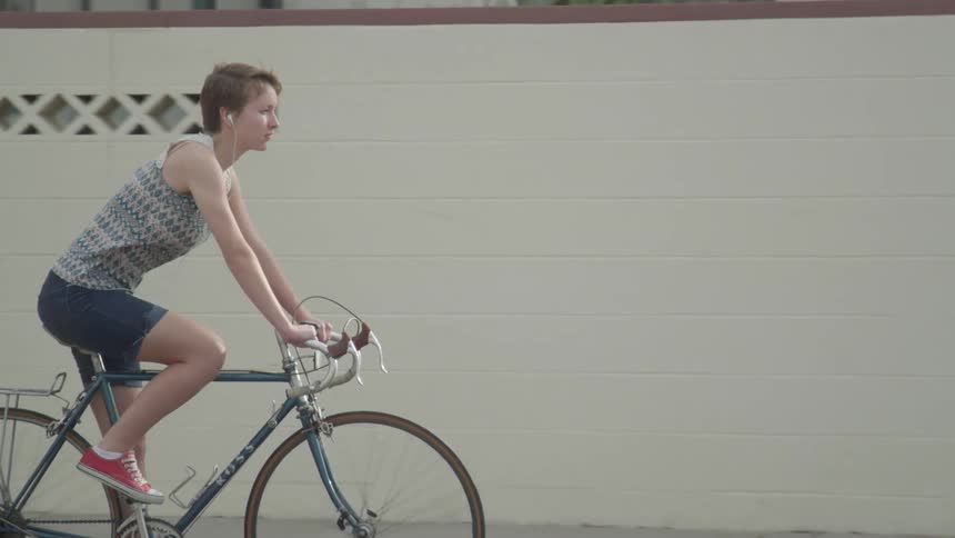 A white woman rides a bicycle in a neighborhood