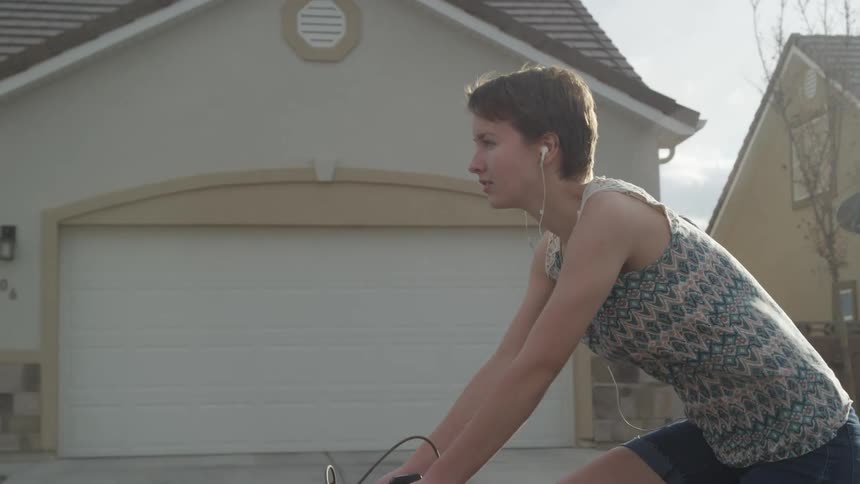 A woman rides her bike past the homes