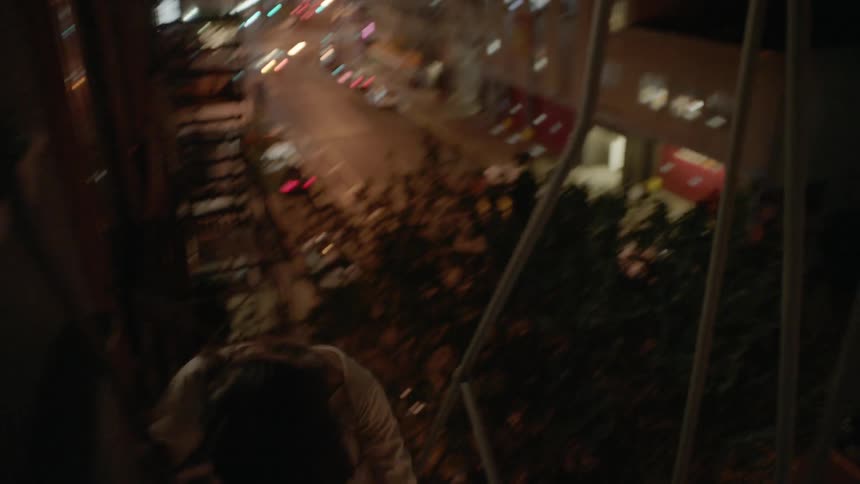 A woman climbs down a fire escape at night