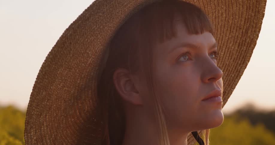 Close up of woman wearing sun hat posing in field of yellow flowers