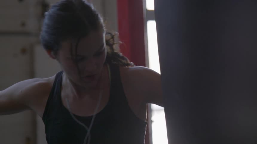 Woman punches a punching bag in the gym