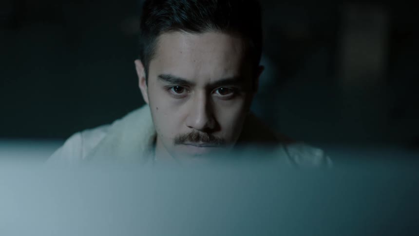 A man is sitting indoors at night