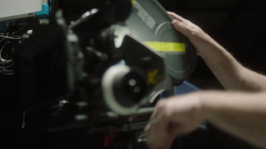 A white man turns dials and adjusts a film camera
