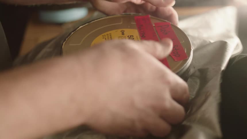 A person puts a label on a roll of film