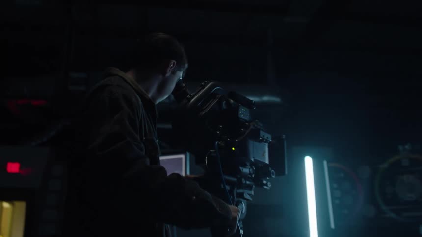 A man in a studio looking into a camera and adjusting it