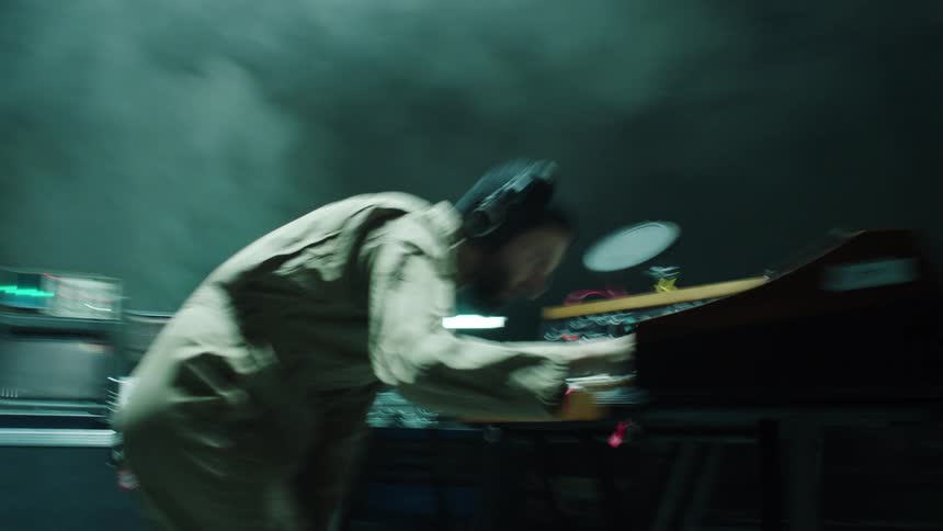 A man is playing the keyboard near a studio setup