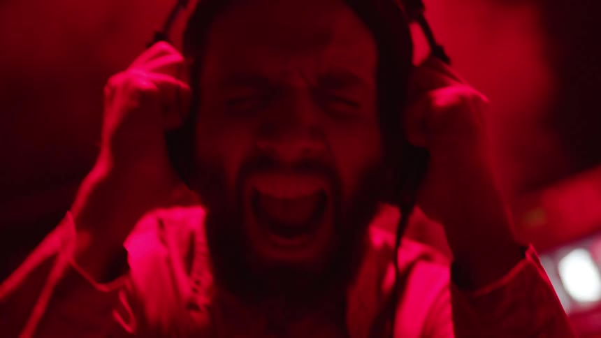 A man holds the headphones on his ears and yells as lights flash