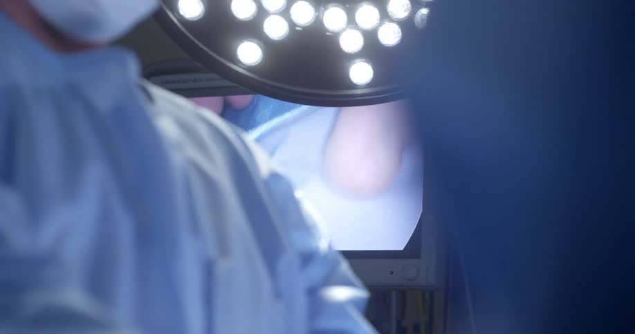 Surgeons performing surgery near a television screen