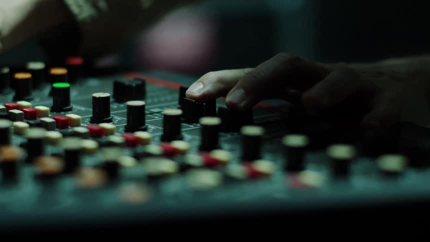 A man pushes controls on a sound board