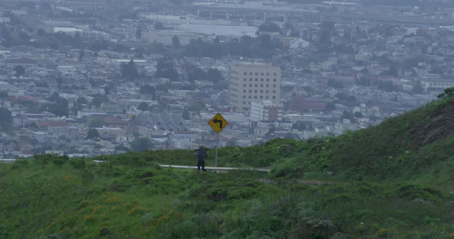 A woman runs down a street with the city skyline in the distance