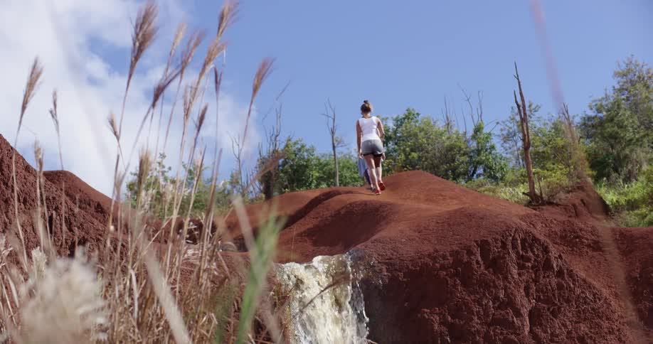 Two women hike past a waterfall in a canyon