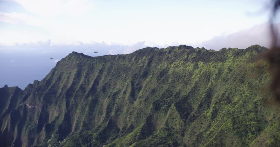 A person watches a helicopter fly over the mountains