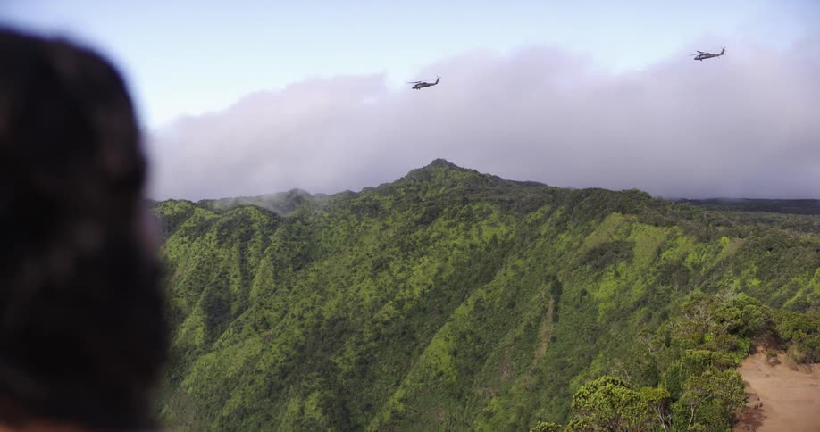 Two helicopters fly over the mountain