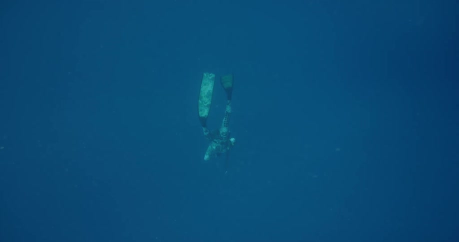 Diver diving deep down into the ocean