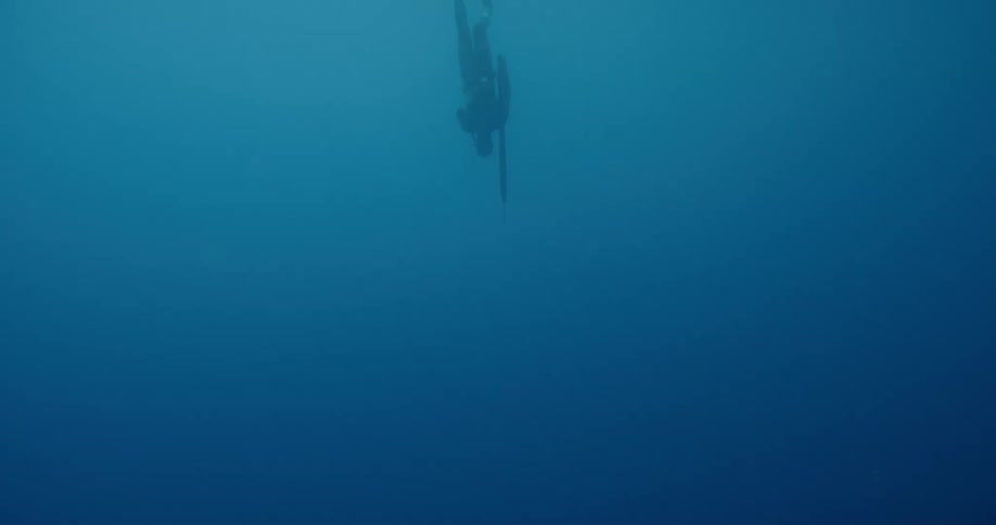 Scuba diver swims underwater on the blue waters of the ocean