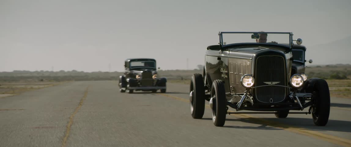 Vintage and antique cars driving down a rural road