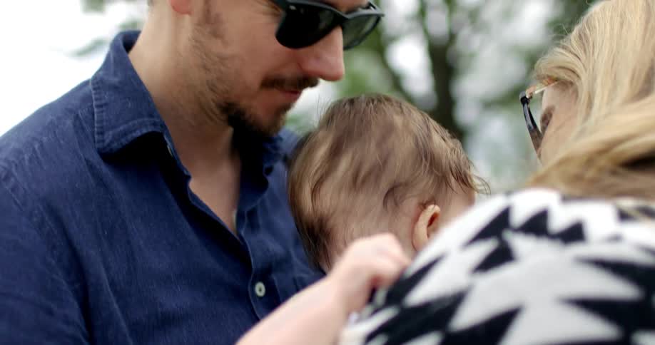 A mother and father hold and kiss their toddler daughter