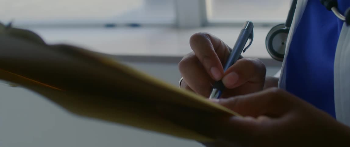 A doctor is writing on a clipboard
