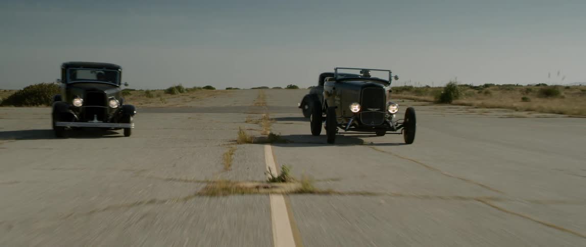 Three vintage cars make a sharp turn as they race
