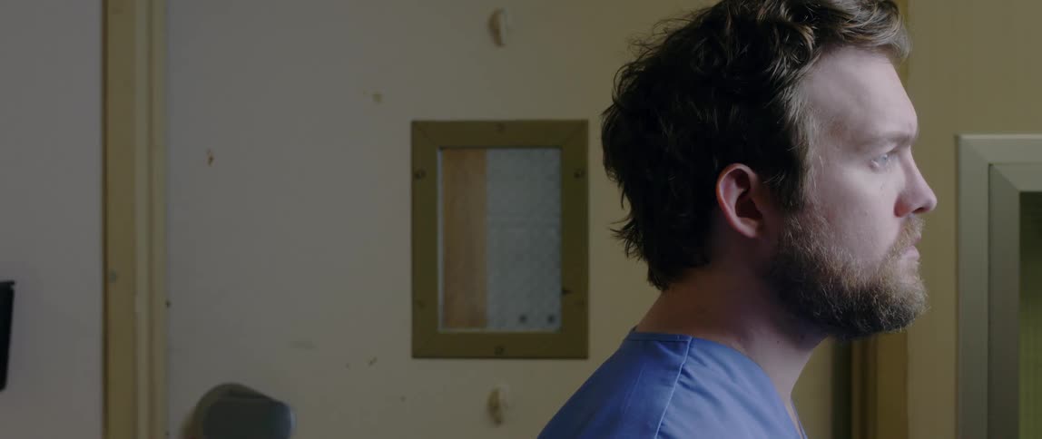 Close up of bearded man face standing in a room looking out a window