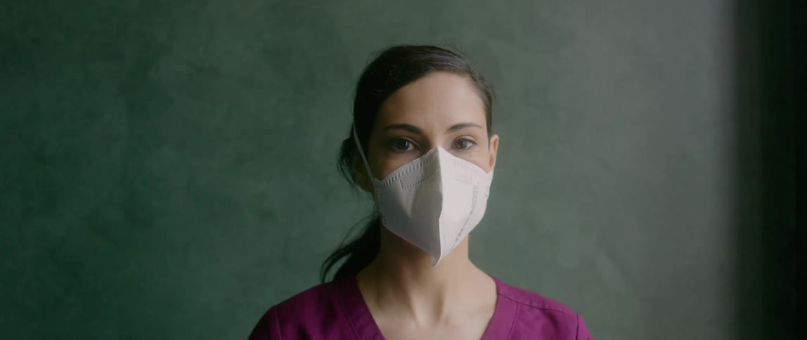 A woman in medical scrubs looks up