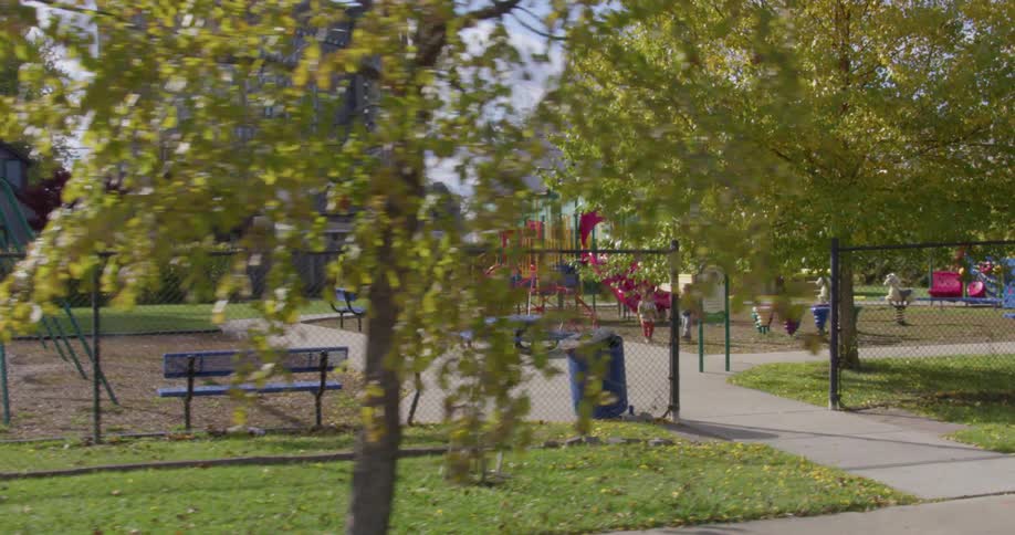 A mother and children play in a playground surrounded by houses and buildings