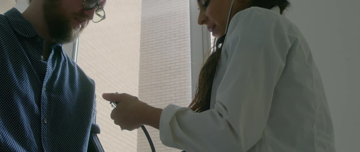 A doctor talks to a man as she takes his blood pressure