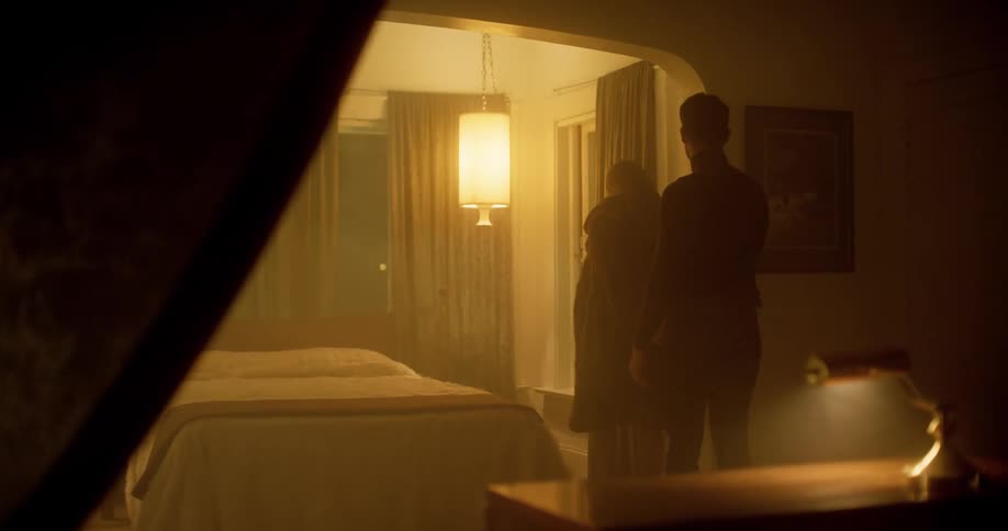 A woman holds her boyfriends hand as she walks him into the bedroom