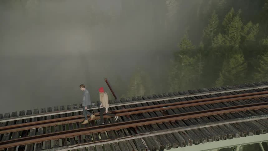 People walking on a train trestle while fog clings to evergreens below the tracks