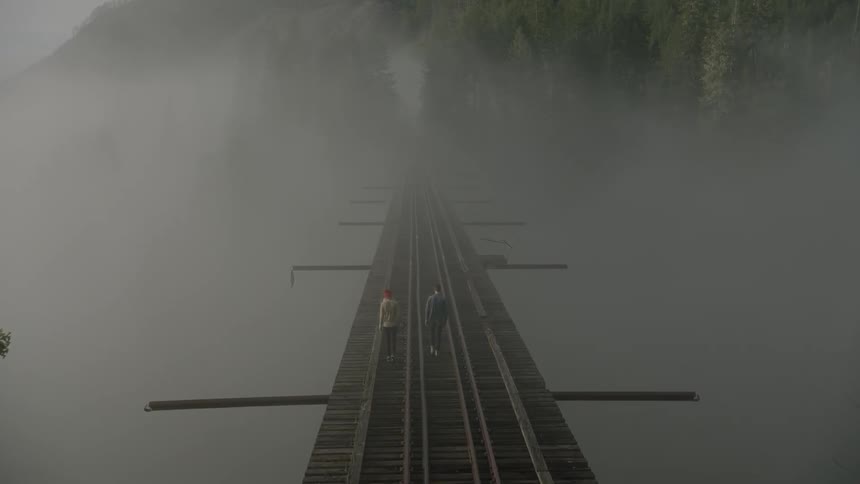 People walk across a railway bridge high above a valley