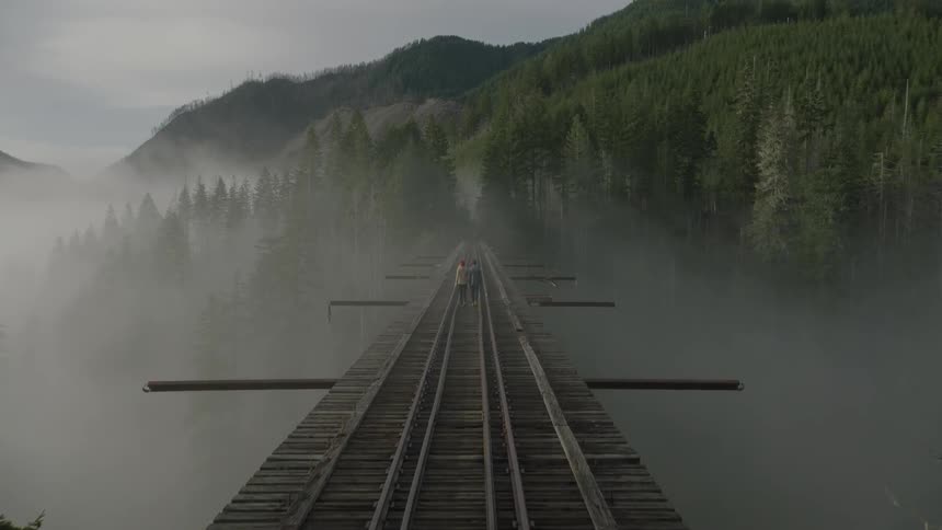 People are walking over train tracks on a bridge