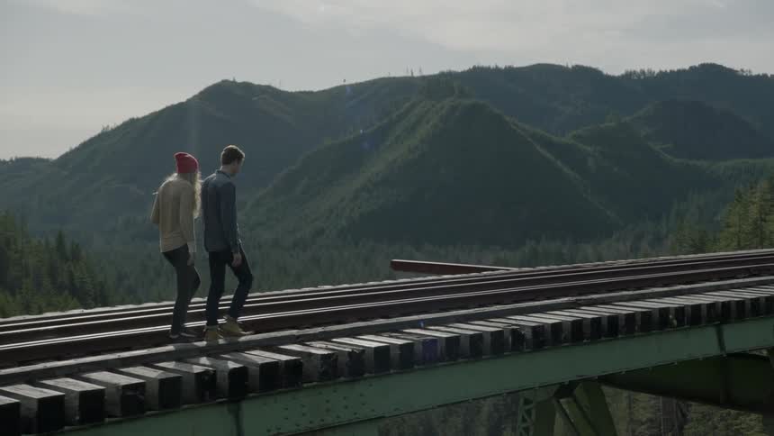Two people are walking along a bridge on a cloudy day