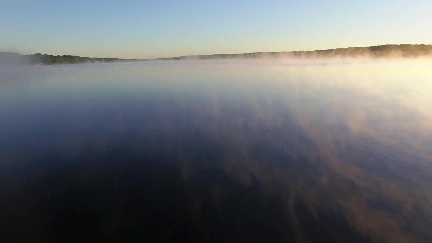 Fog rises from a lake at dawn