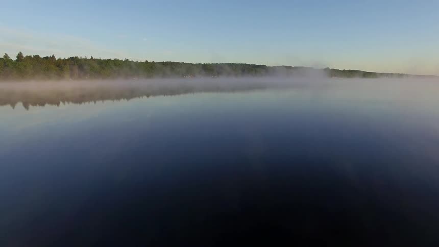 Aerial footage of a pier jutting out into calm, misty-covered water