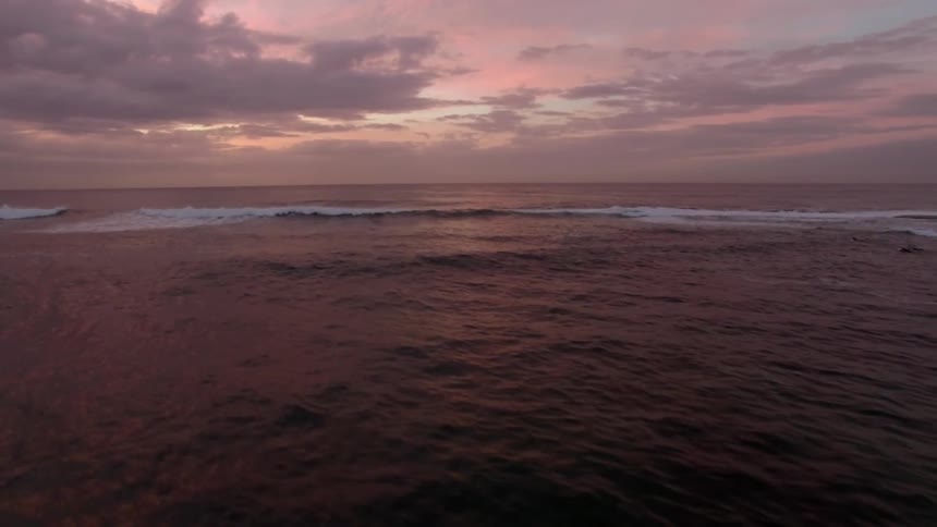 Waves cresting under a cloudy sky during sunset