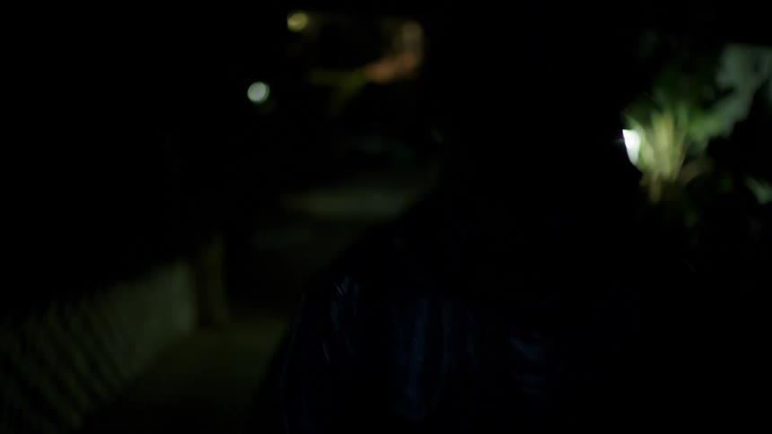 A person walks outside as lightning flashes