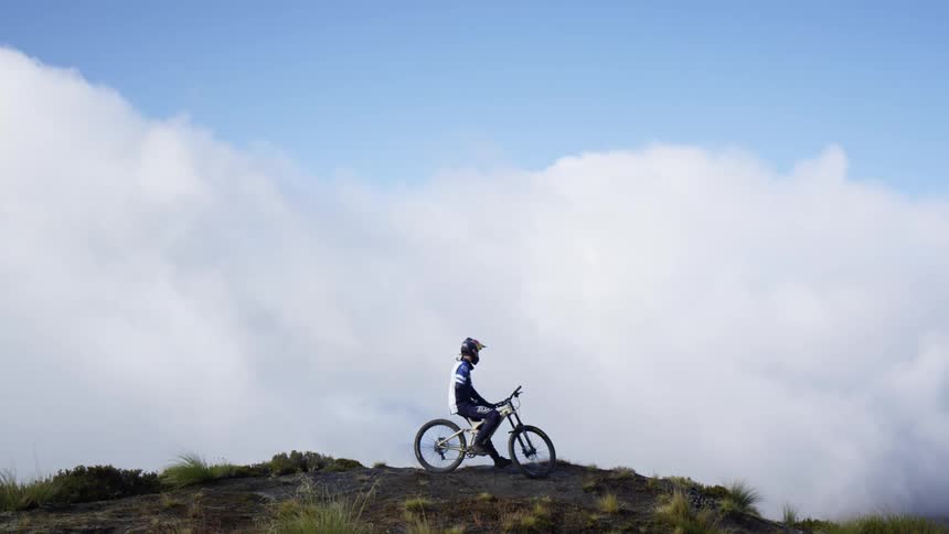 A person on a mountain bike rests on the top of a hill
